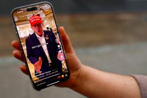 A woman poses with a smartphone displaying the @realdonaldtrump TikTok page in Washington, USA