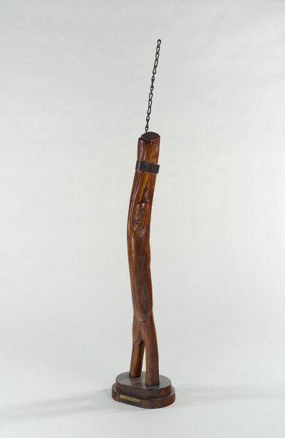 The sculpture of polished wood shows slightly carved faces and chains rising suggestions. 
