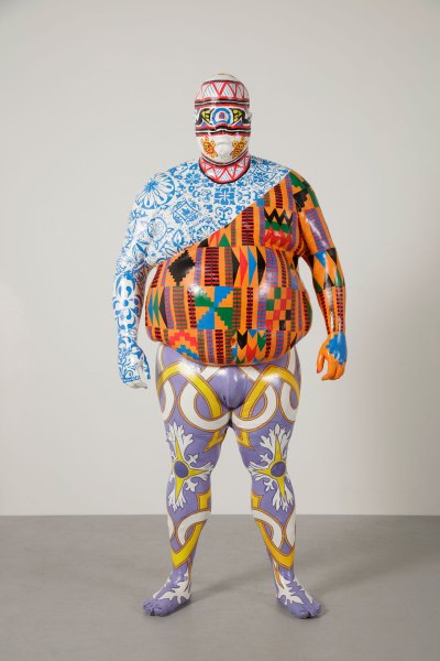 A life-size sculpture of a man with a larger belly. He paints in various modes, representing different races 