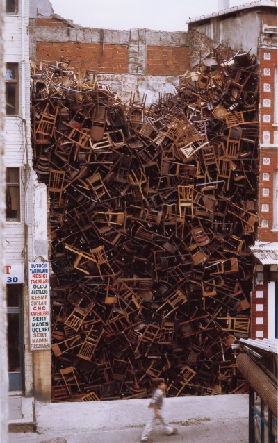 A pile of chairs in between two buildings.