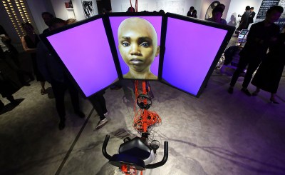 An exercise bike with a three-screen monitor showing a Black woman's computer-generated avatar.