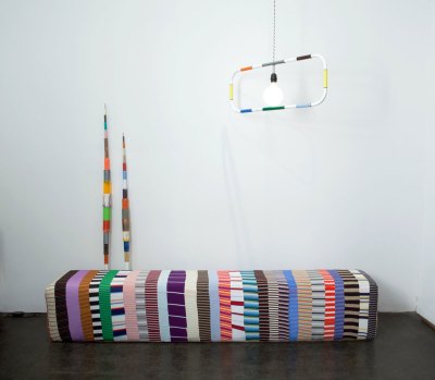 In the corner of the art fair stall, there are several artworks with various colours and fabrics.