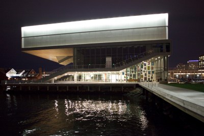 The top floor of a museum hangs on a nearby harbor.