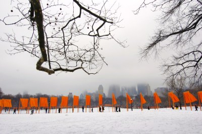 A series of saffron-colored portals, flowing fabrics hanging from the snow.