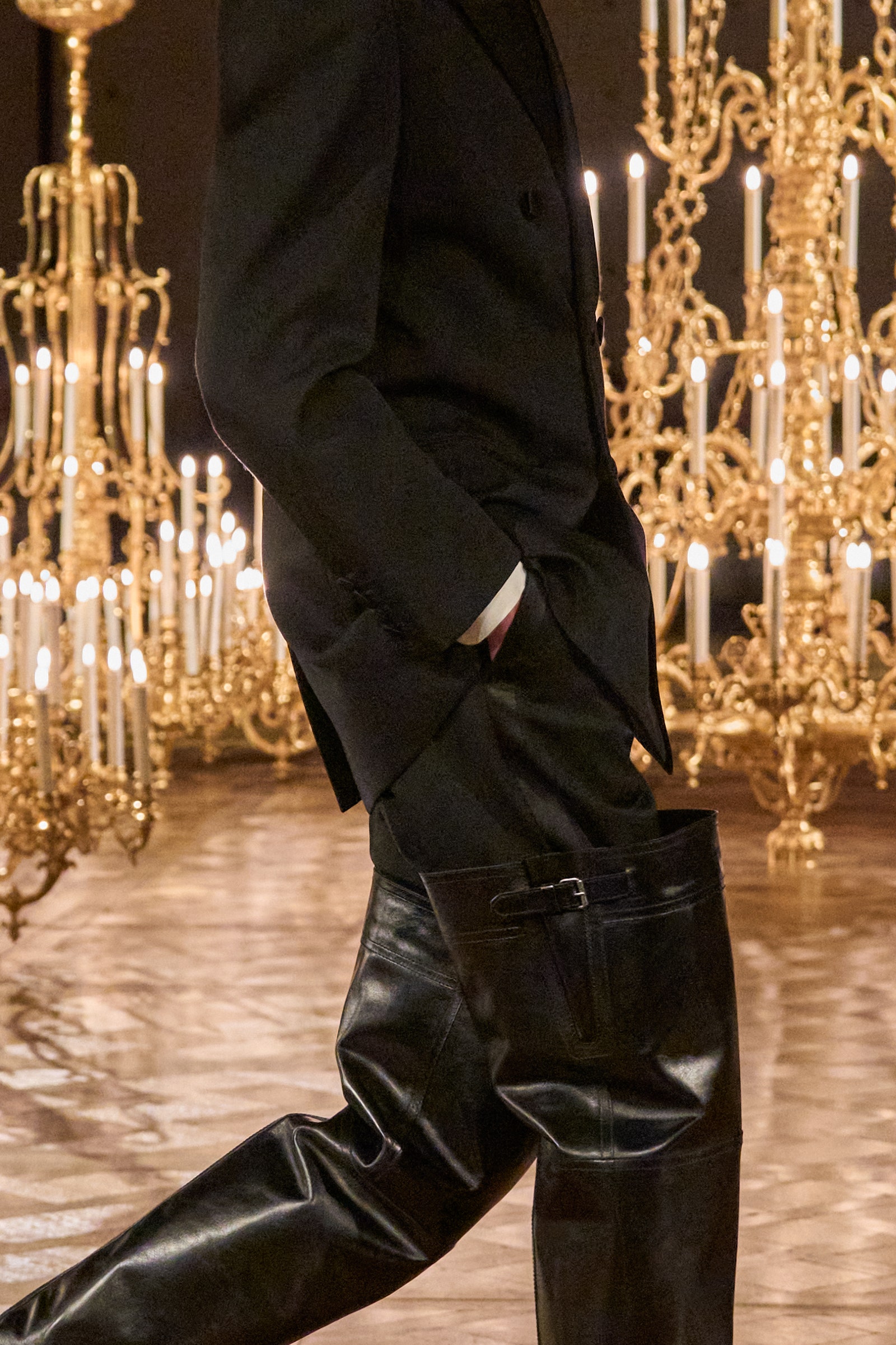 Image may contain Chandelier Lamp Clothing Pants Adult Person Footwear Shoe Coat and Candle