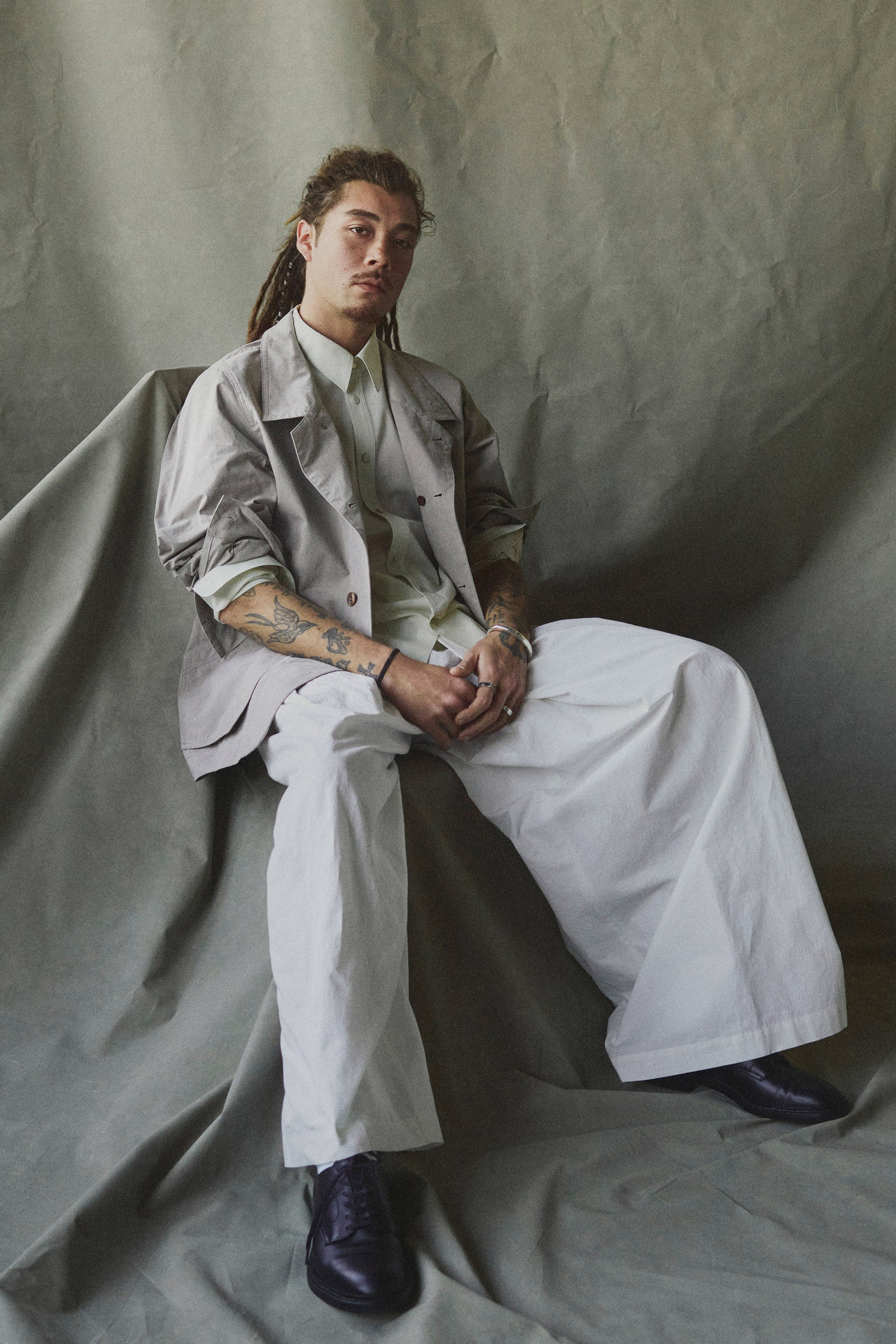 Image may contain Person Sitting Clothing Coat Footwear Shoe Adult Pants Accessories Bracelet Jewelry and Face