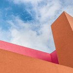 Detailed views to the exterior of the postmodern building with orange and pink walls.