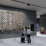 The installation landscape in the museum lobby shows people standing in front of the installation consisting of reindeer skulls.