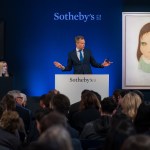 A man stood behind the podium with both sides of the painting.