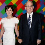 A man in suit and a woman in clothes before wearing large abstract painting.