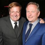 Two men in suits smiling at the camera.