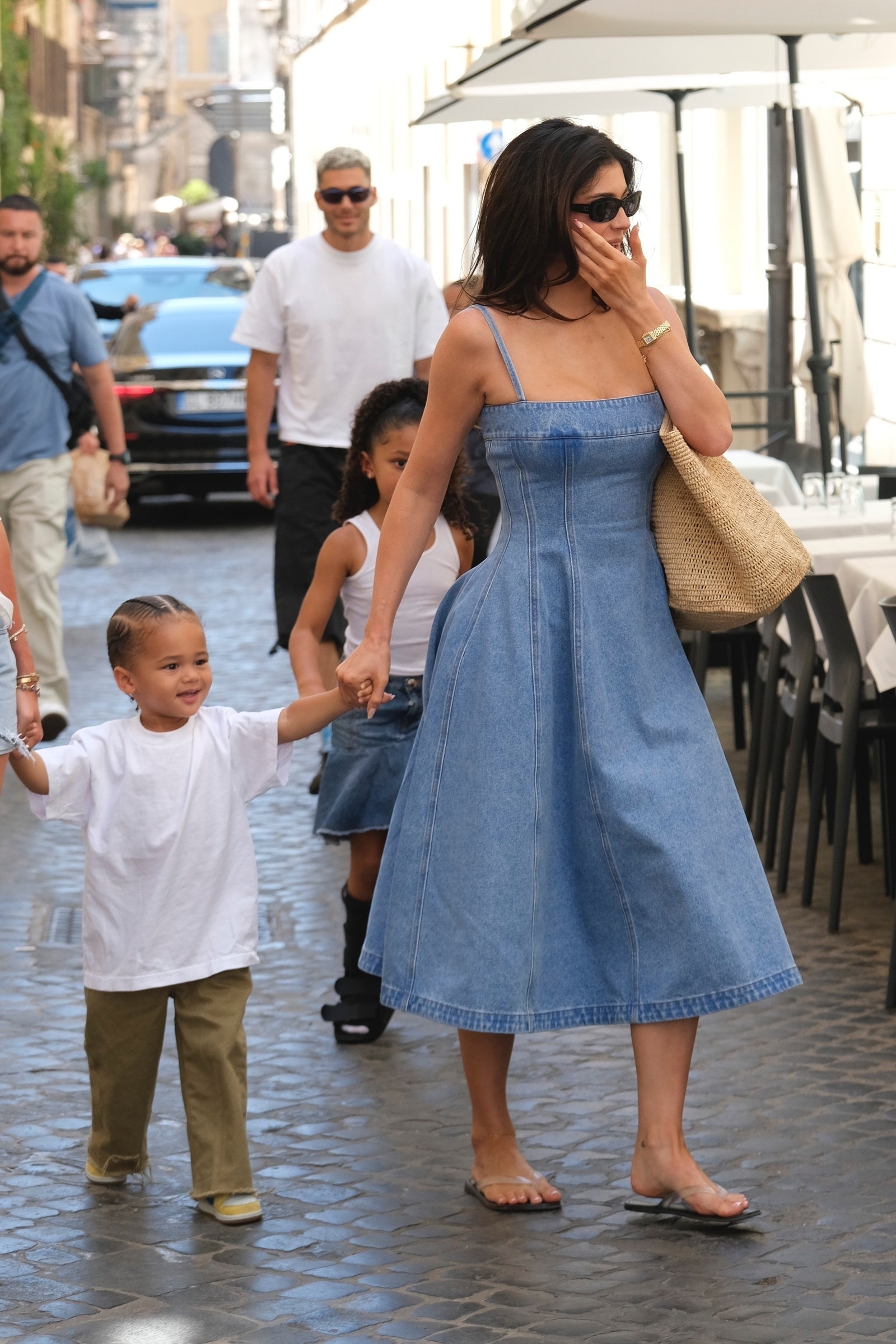 Image may contain city street city clothing pants dress people walking shoes children and adults