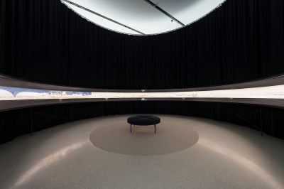 The bench in the center of the gallery, the walls are pounded by artworks that resemble scrolls.