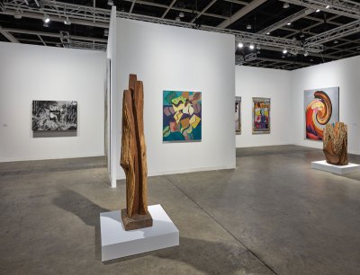 The view from the gallery booth of the Museum of Art Gallery shows several paintings on the wall and there are two parts carved wood carvings on the base. 