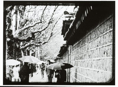 A movie still shows people holding umbrellas in a snowy day beside the walls of the Korean palace. 