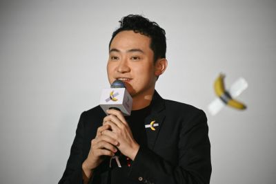 A man standing in front of a banana tube on the wall holding a microphone. 