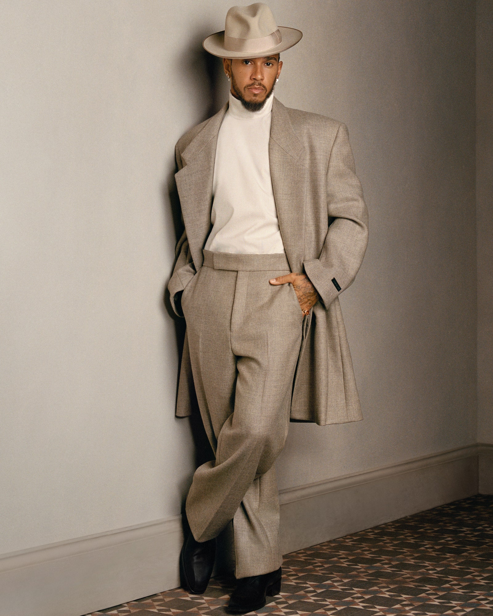 Images may contain Lewis Hamilton clothing formal clothing blazer hat jacket adult and blazer