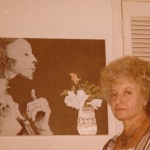 A woman stands next to a mummy on the wall.
