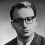 Black and white photo of man in suit wearing glasses.
