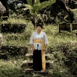 Portrait of Citra Sasmita stands outside a lush area.
