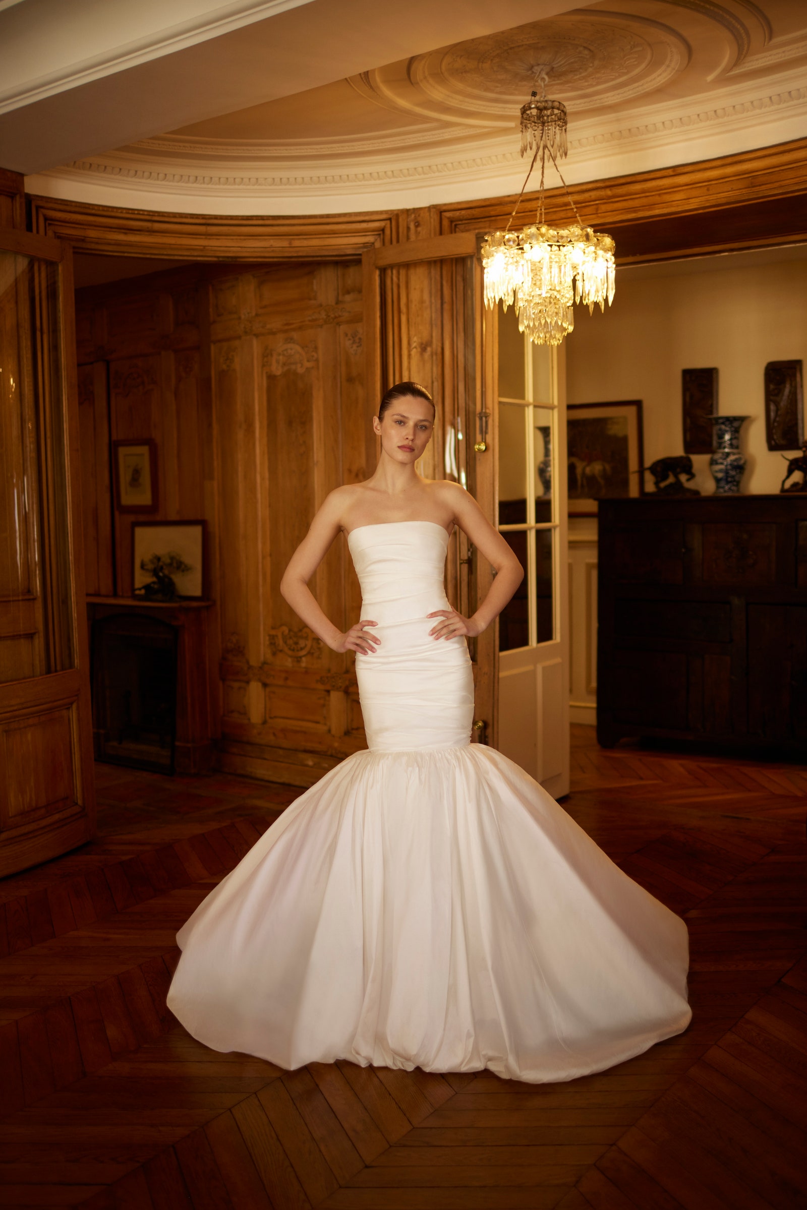Images may contain clothing dress formally wearing chandeliers hardwood wood floors fashion and gowns