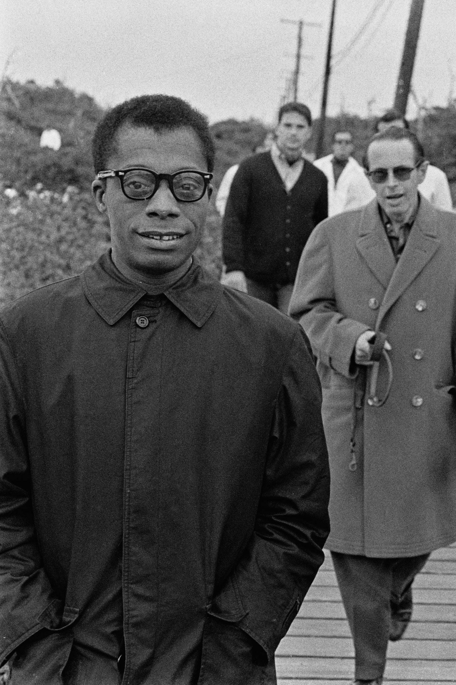 Images may contain James Baldwin clothing jacket boardwalk bridge seaside man walking and adult