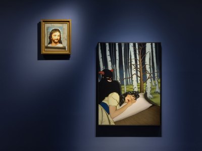 Two paintings hang on a blue wall. The smaller one on the left is the breeding painting of Jesus Christ. The larger person on the right has a Snow White figure in the forest, and a demon-like figure looks at her.