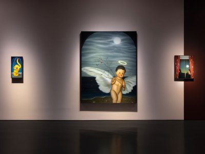 There are three different sized views hanging in the art gallery. From the left, a yellow elephant; an angel figurine of the ocean; a woman looking at the window behind the curtains.