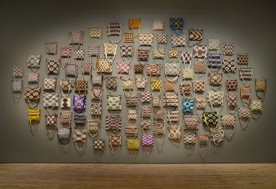 A set of 100 bags hang on the wall.