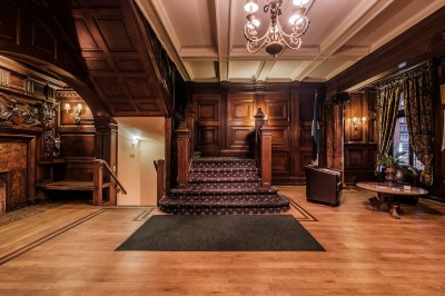 Wood paneled walls and a wooden floor with a chandelier.