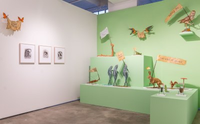 Many animal sculptures holding signs of protest are situated on a wide green pedestal.