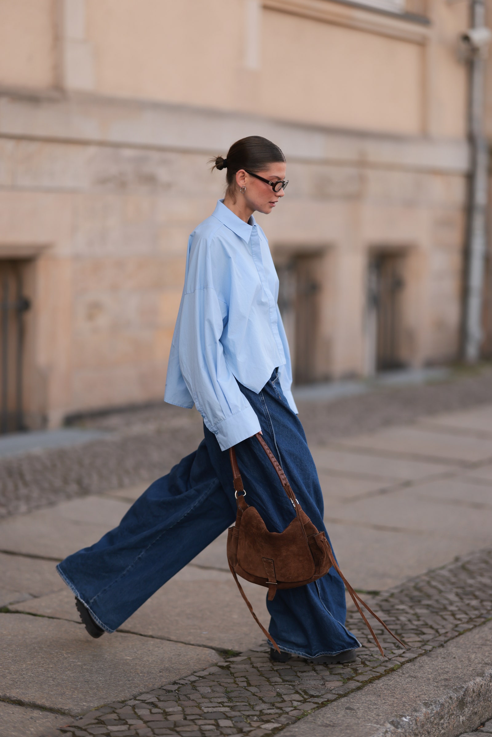 Image may contain people walking jeans accessories bag tote bag adult shoes shoes and blazer