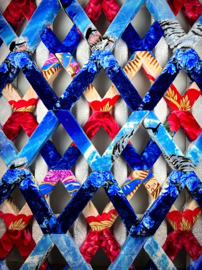 An artwork with a lattice design made of fleece blankets over foam. 