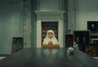 The nun prays on the table. Behind her was the painting leaning against the stone wall.