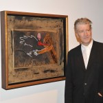 A man in a suit next to a painting of a smoking pipe and a hand.