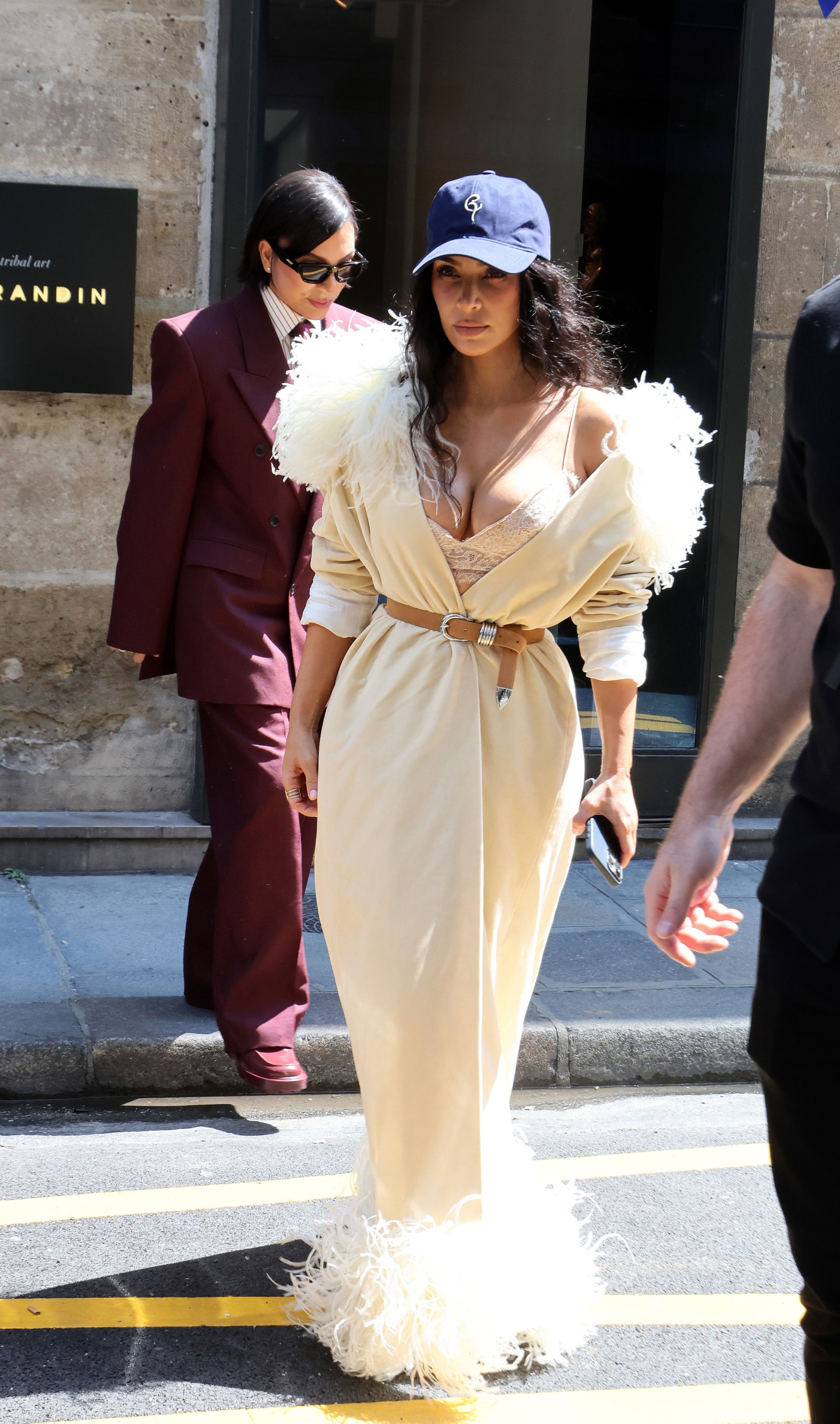 Images may contain Kim Kardashian Electronics Mobile Phone Clothing Hat Hat Officially Wearing Adults and Humans