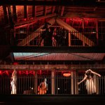 The upper level of industrial buildings shows three performances, moving their bodies to the upper level, while the camera crew films them on the level above.