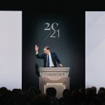 A man stands on a podium and bids.