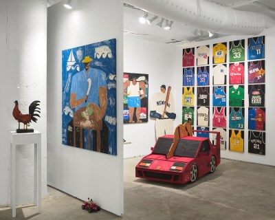 An art fair stall with a painting of a red wooden car and sports jersey in the center.