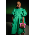 Happy woman in green dress wearing pink purse.