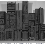 A sculpture consisting of many black boxes with something black inside.