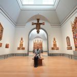 A man sitting on a bench in a room full of religious idols.
