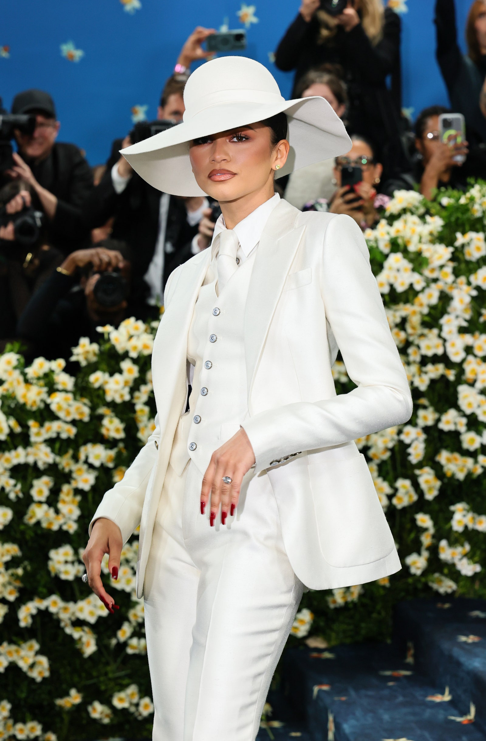 Images may contain Zendaya personnel clothing hat accessories jewelry ring camera electronics formal wear and suit