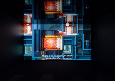 Installation view of a film work in a black box showing an industrial construction. 
