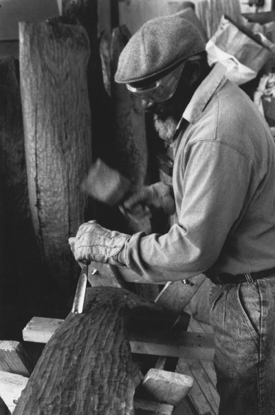 A black man waving a chisel on a piece of wood.