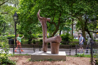 A bronze sculpture resembles wood in a park.