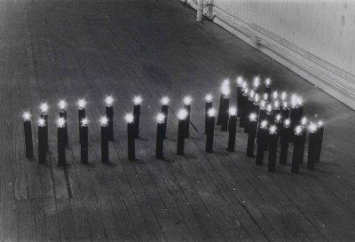 A black and white photo showing cross-cut shapes made of bright and dark candles.  