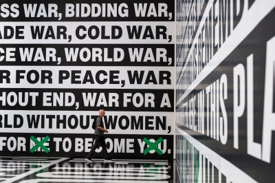 A man walks through an installation, and his walls are completely covered with text.