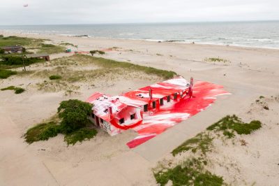 A beachfront house covered in red and white paint.