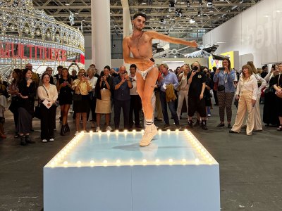 A boy in silver-skinned lamesus dances on a blue platform.